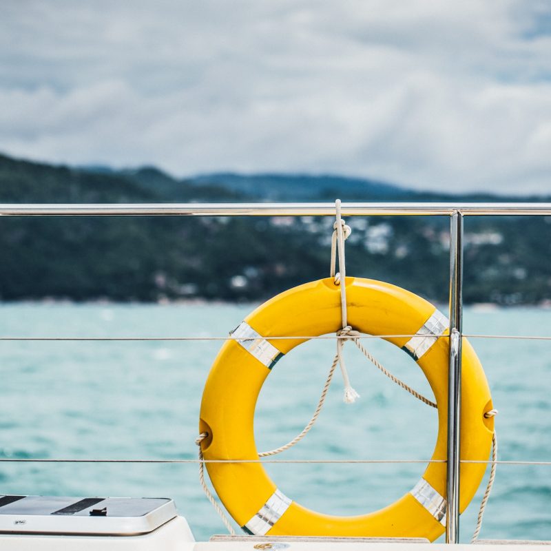 Close-up Yellow life ring hanging on boat with ocean background
